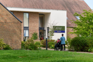 nurse pushing a resident in a wheelchair into the neurological care centre in Crawley