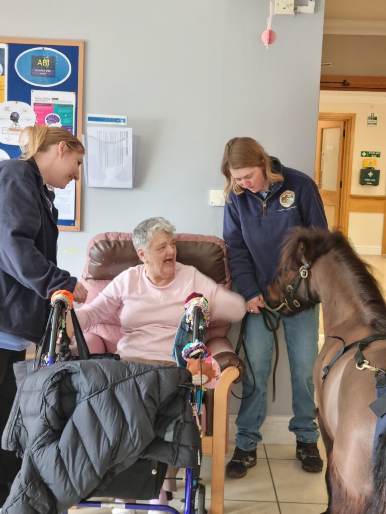 happy care resident petting pony